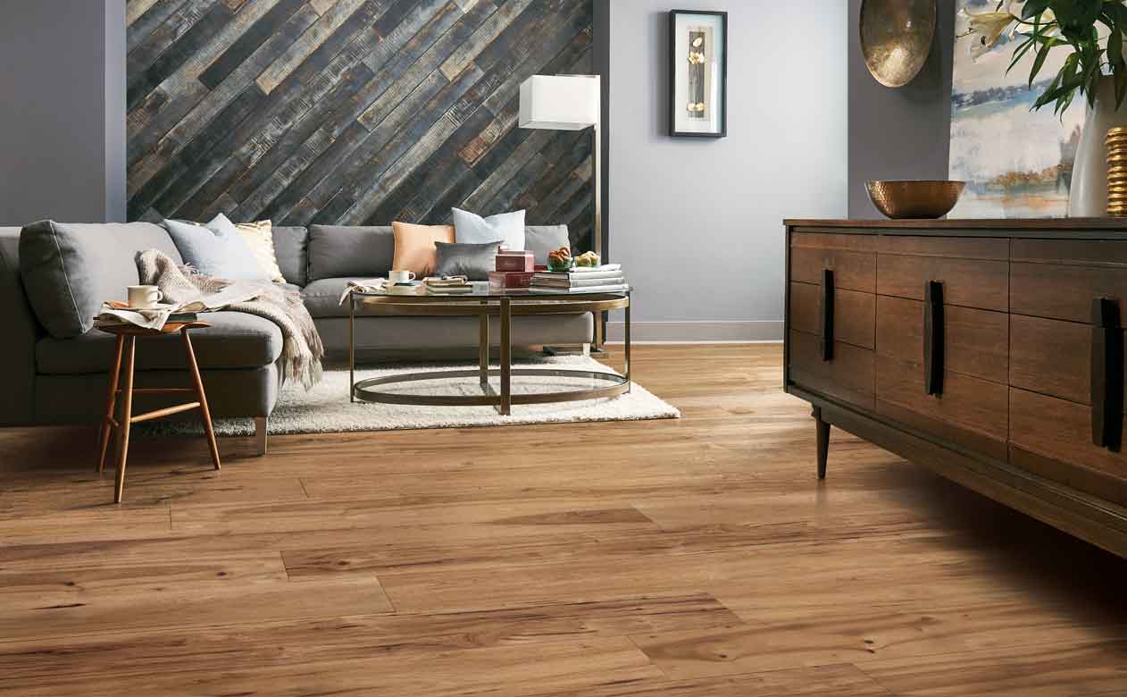 honey hued Hardwood Flooring in Living Room with gray plank accent wall, gray couch and coffee table