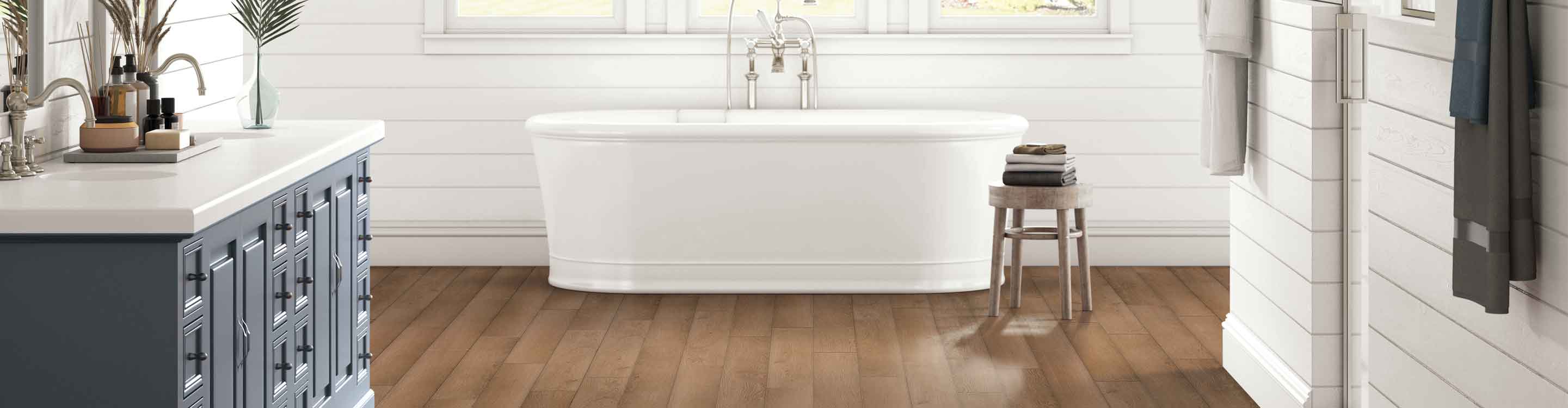 medium toned vinyl flooring in bathroom with white shiplap walls, deep soak tub, blue vanity and wood accents